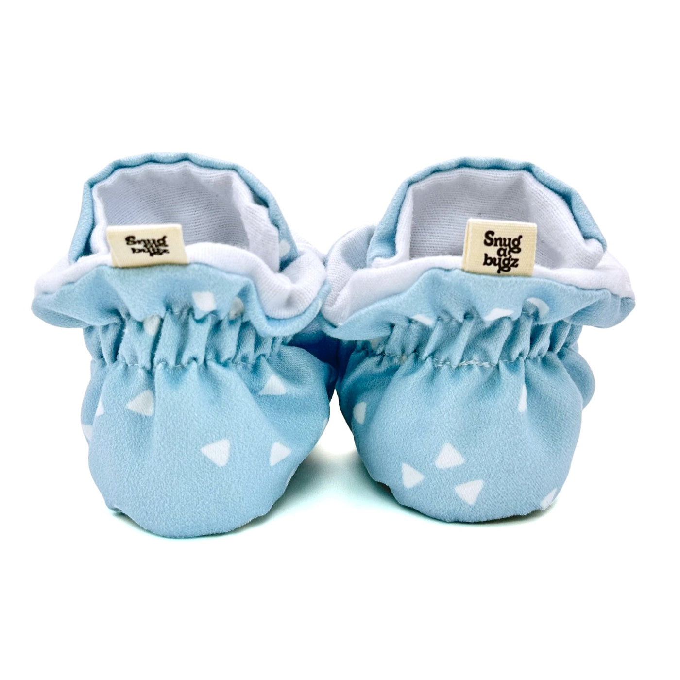 Stay-on baby booties featuring white triangles on a baby blue background print, with non-slip soles and adjustable three snap closure. Made from organic cotton.