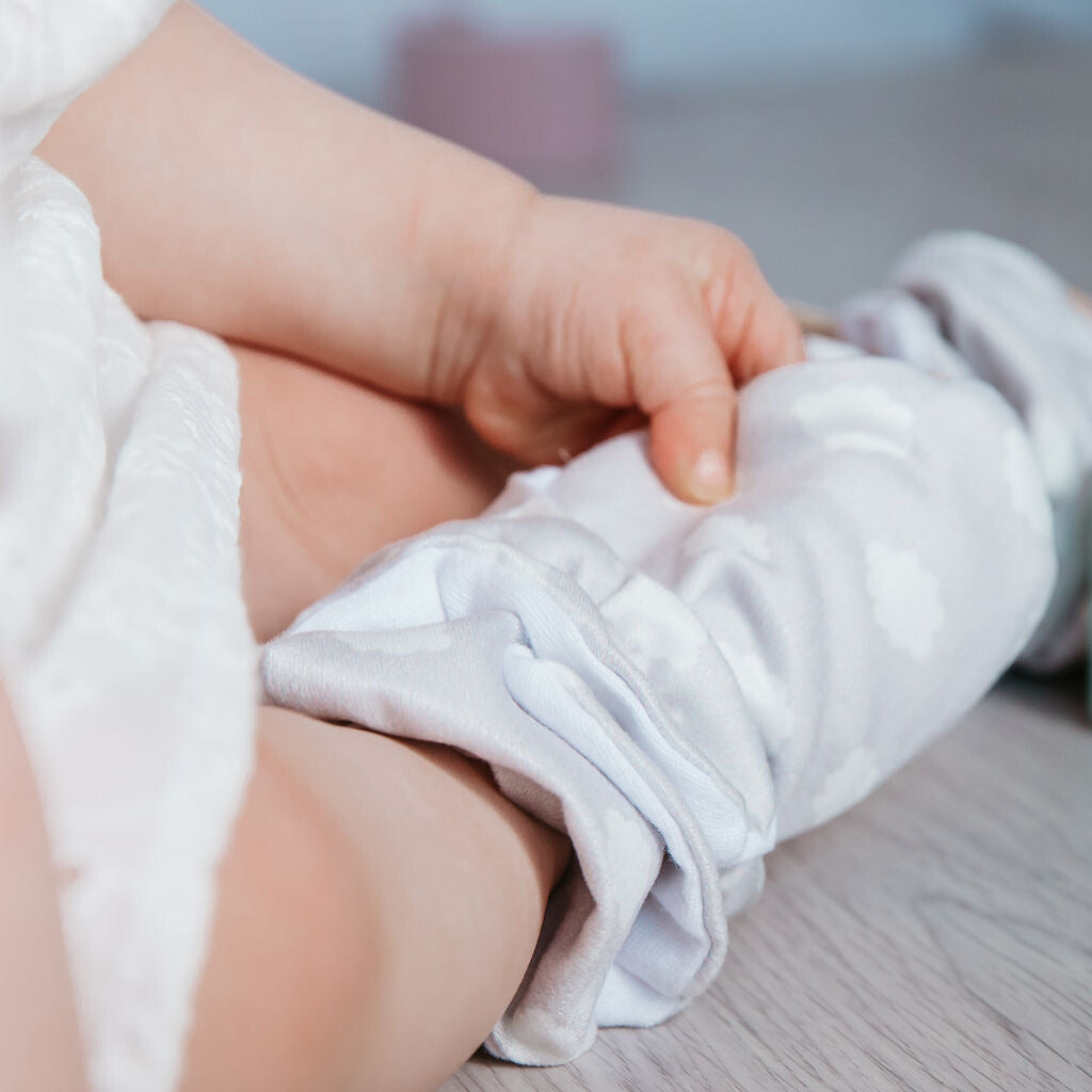 Snugabugz stay-on baby booties with a neutral grey clouds print, with non-slip soles and adjustable snap closure. Made from organic cotton.